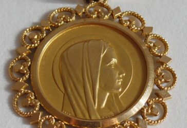 Un pendentif en or centré d’une médaille de la Vierge en or.