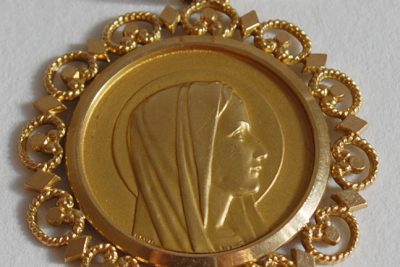 Un pendentif en or centré d’une médaille de la Vierge en or.