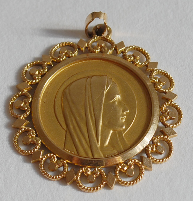 Un pendentif en or centré d’une médaille de la Vierge en or.