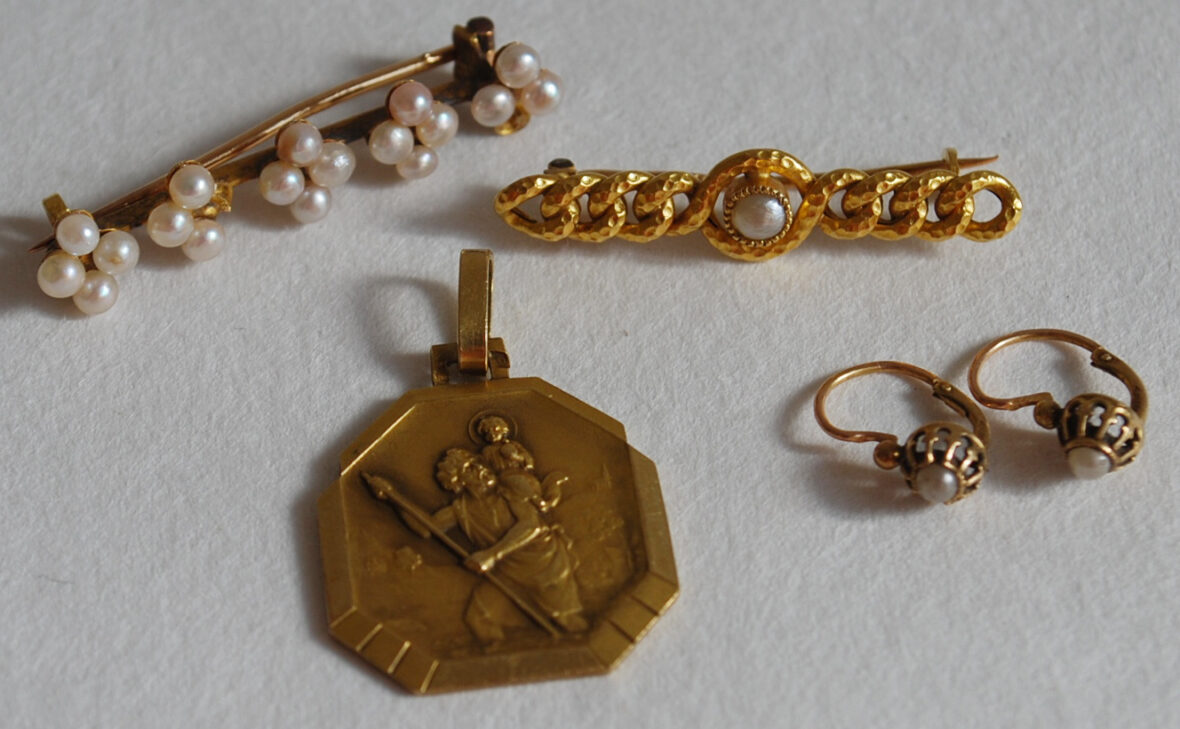 Ensemble formé de deux broches ornées de petites perles, une médaille à décor de Saint Christophe, une paire de dormeuses.