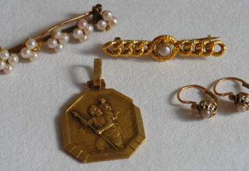 Ensemble formé de deux broches ornées de petites perles, une médaille à décor de Saint Christophe, une paire de dormeuses.