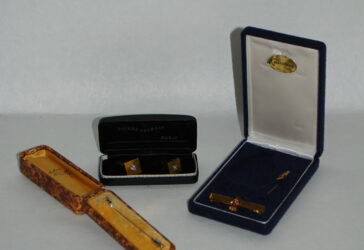 Lot de bijoux comprenant : - une paire de boutons de manchettes en métal doré avec pierres interchangeables PIERRE BALMAIN - une épingle de cravate ornée d'une pierre de culture - une épingle et une pince à cravate en métal.