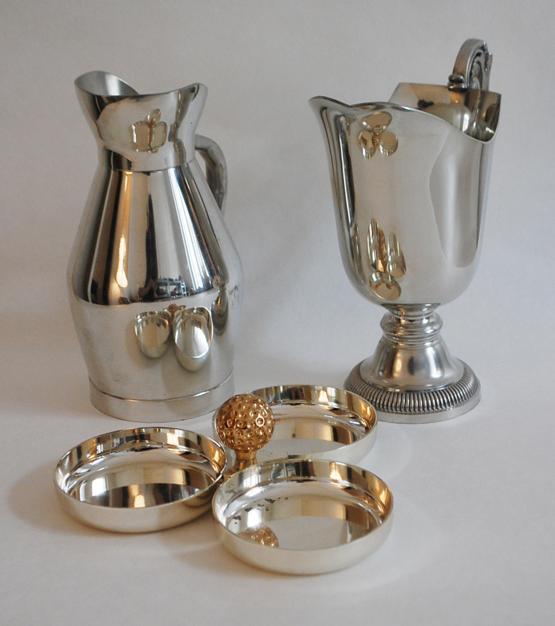 Lot comprenant deux pichets l'un en étain, l'autre en métal argenté et un présentoir en métal argenté et doré.
