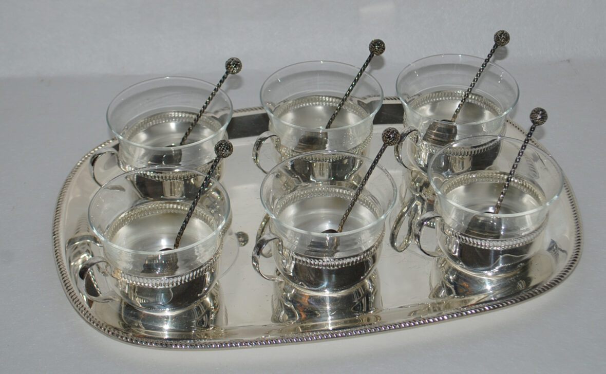 Partie de service à café en métal argenté comprenant 6 tasses en verre monture en métal argenté et son plateau. On y joint 6 petites cuillères.