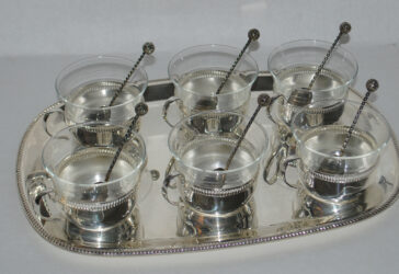 Partie de service à café en métal argenté comprenant 6 tasses en verre monture en métal argenté et son plateau. On y joint 6 petites cuillères.