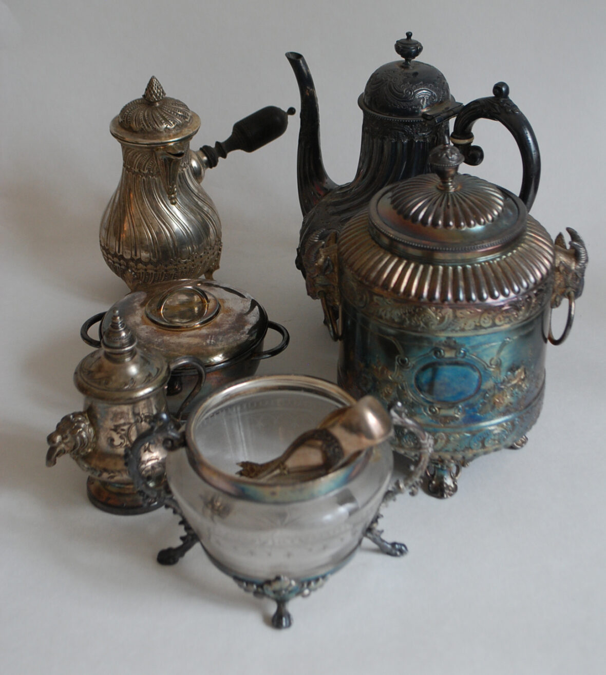 Ensemble en métal argenté comprenant une petite cafetière, une boîte couverte, une théière, un sucrier le récipient en verre gravé (manque le couvercle), une petite fontaine et un sucrier couvert uniplat.