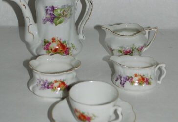 Dinette en porcelaine à décor de fleurs et fruits peints comprenant une théière, un sucrier, un pot à lait, un pot à crème, une tasse et deux soucoupes.