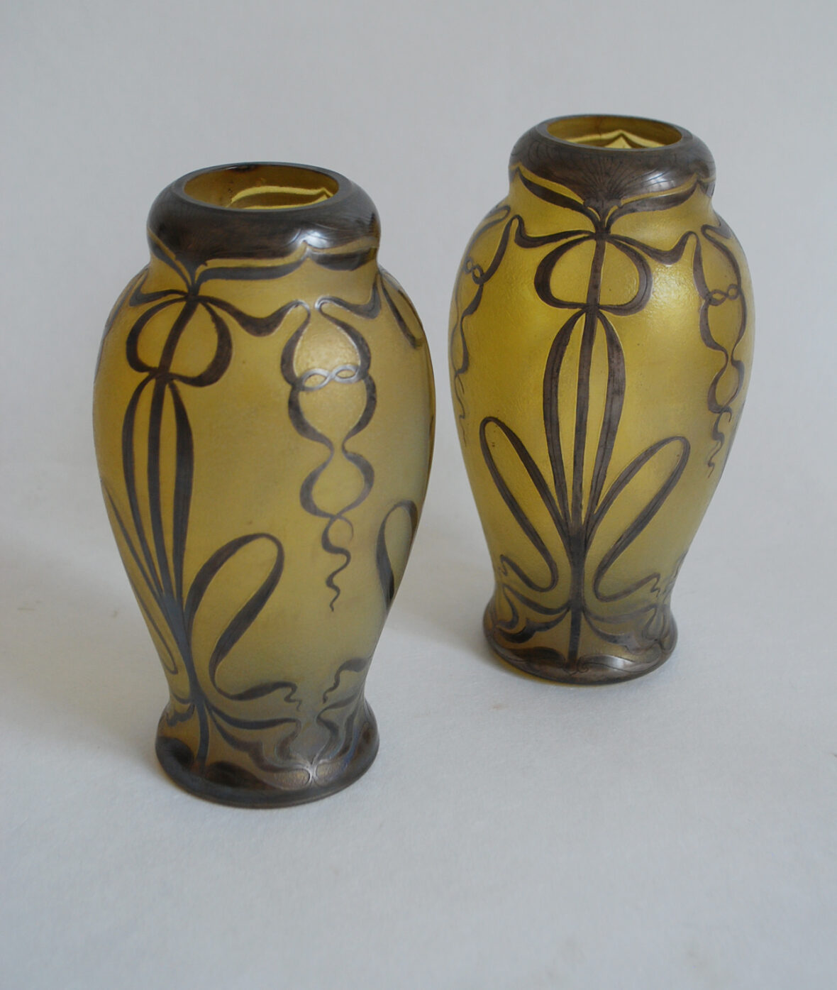 Paire de vases balustres en verre teinté jaune rehaussé d'un décor argenté de passementerie. XXe siècle.