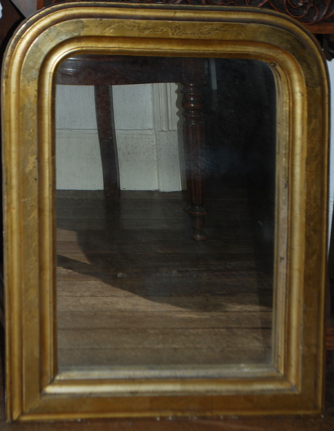 Miroir en bois doré à décor ciselé de feuillages et fleurettes.