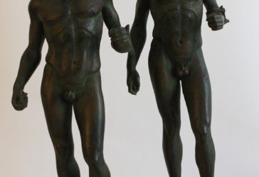 Paire de statuettes en résine représentant les guerriers de Riace, à patine imitant le bronze. Sur un socle en marbre. Numéroté 589/599. XXe siècle.