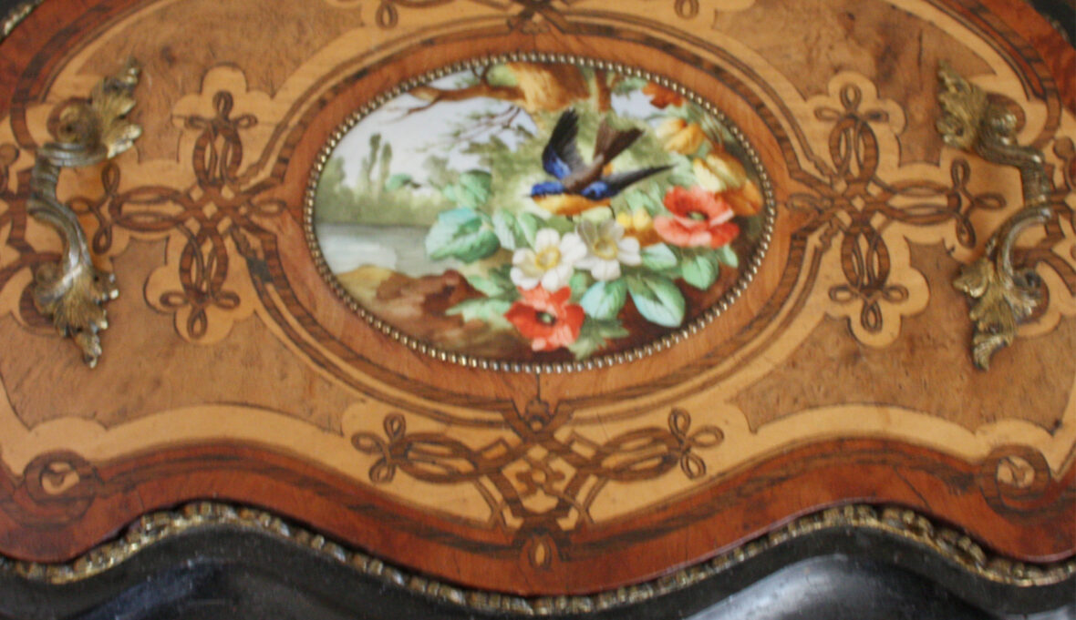 Jardinière en bois noirci et marqueté de forme rognon. Le plateau orné d'un médaillon en porcelaine à décor peint d'un oiseau dans un paysage fleuri. Époque Napoléon III.