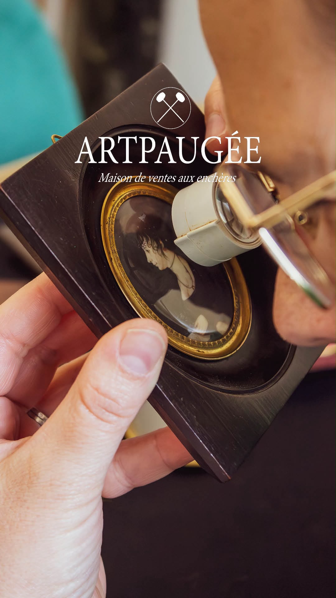 Commissaire-priseur examinant à la loupe un portrait miniature ancien encadré, lors d’une expertise à l’étude Artpaugée.